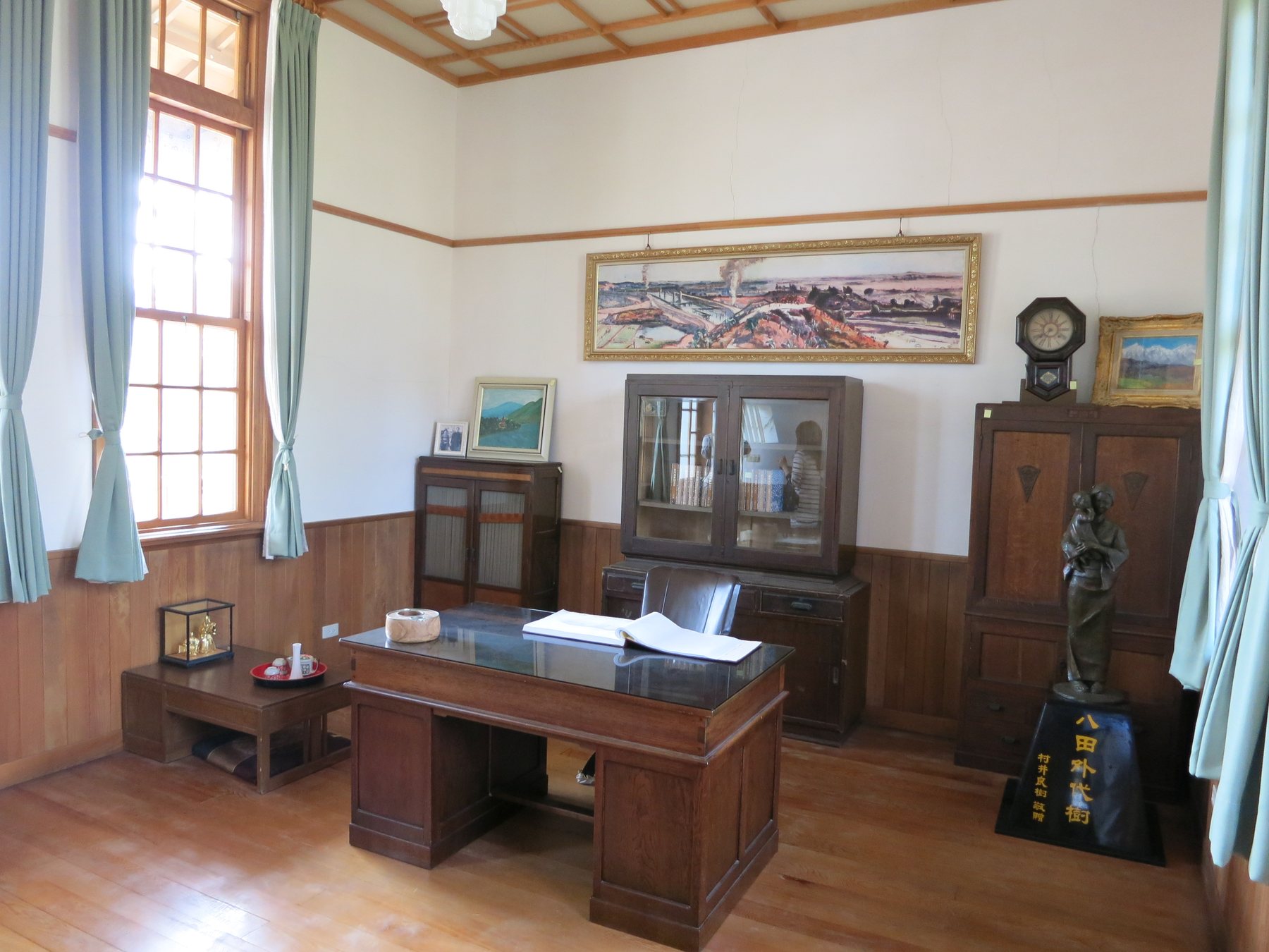 The study inside the Hatta residence, with a wooden desk, bookcase, clock, and furnishings