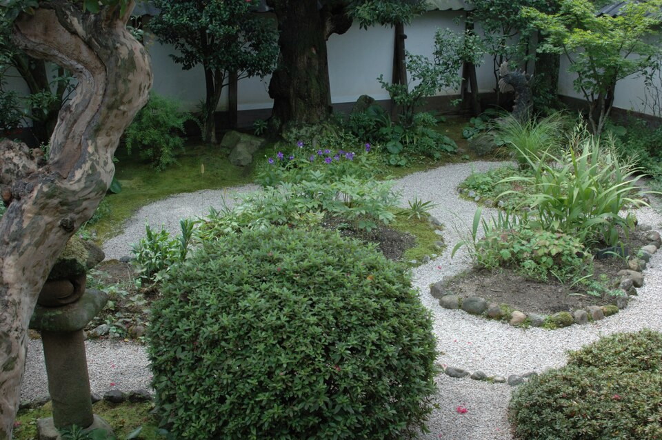 The front garden of Lafcadio Hearn's former residence in Matsue, with a pale path, garden stones, shrubs, and trees
